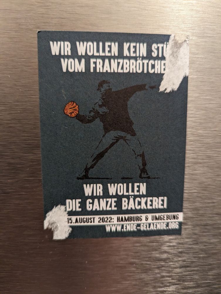 Ein Aufkleber mit dem Titel "Wir wollen kein Stück vom Granzbrötchen. Wir wollen die ganze Bäckerei" mit der Abbildung einer schwarz gekleideten Person, die ein Franzbrötchen wirft.