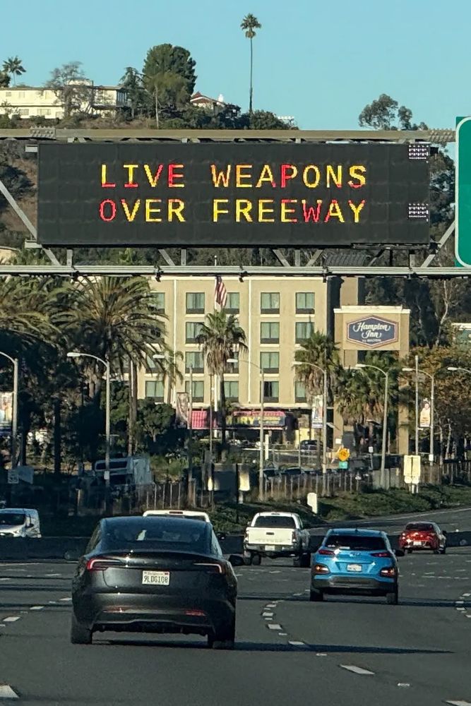 Photo shows a sign over California, U.S. highway which reads “LIVE WEAPONS OVER FREEWAY” where a missile detonated overhead and rained shrapnel on the road, hitting Vice President JD Vance’s security detail 
