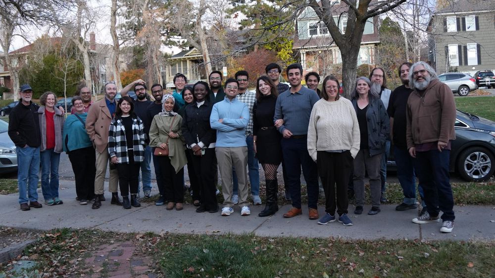 A group of about two dozen people, mostly faculty and graduate students, standing outdoors for a group photo