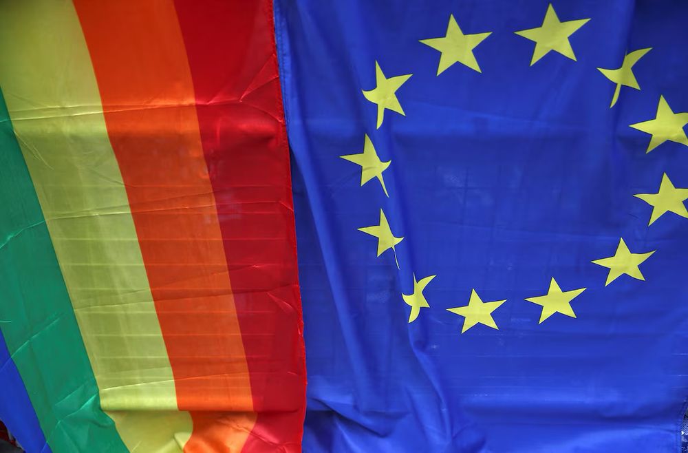 A European Union flag is displayed alongside a Rainbow flag during the annual Pride London Parade
