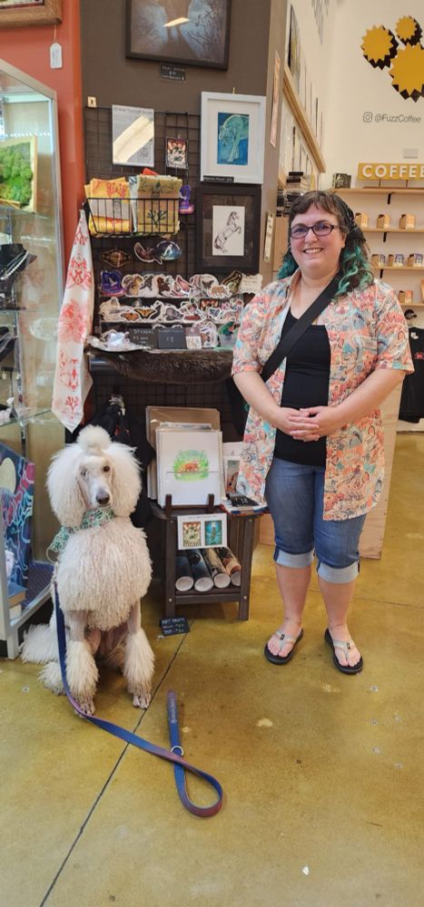 Me and a white (slightly damp) poodle standing next to my art retail booth at Sea Hive 