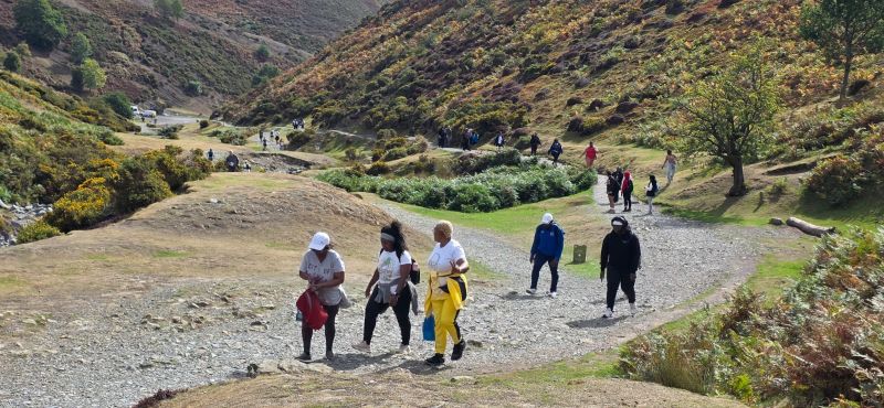 Waka Waka founder Dorothy (in yellow) and fellow community members make their way through the valley with hills either side of a gravel path.