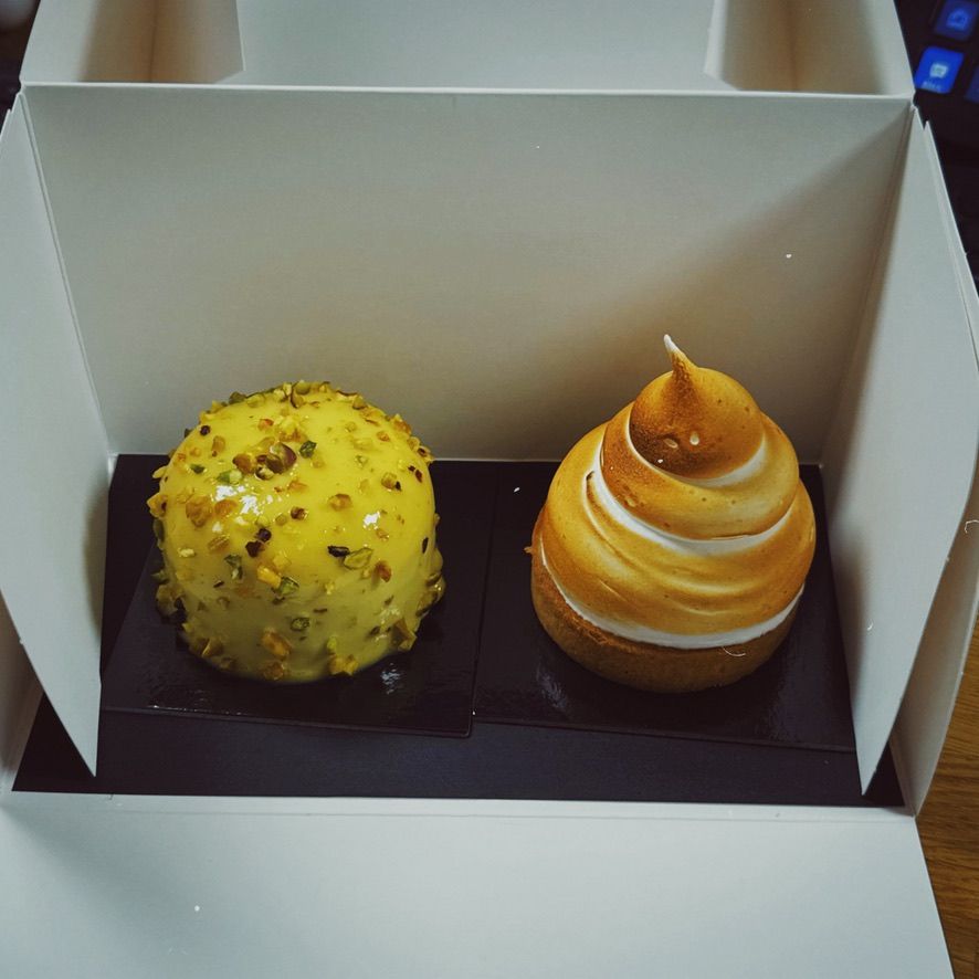 A picture of two small cakes, left on is full pistachio, right one is lemon
