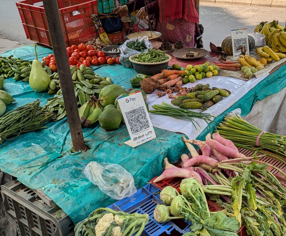 A grocer's stand on a street in Kolkata with a Google Pay QR code