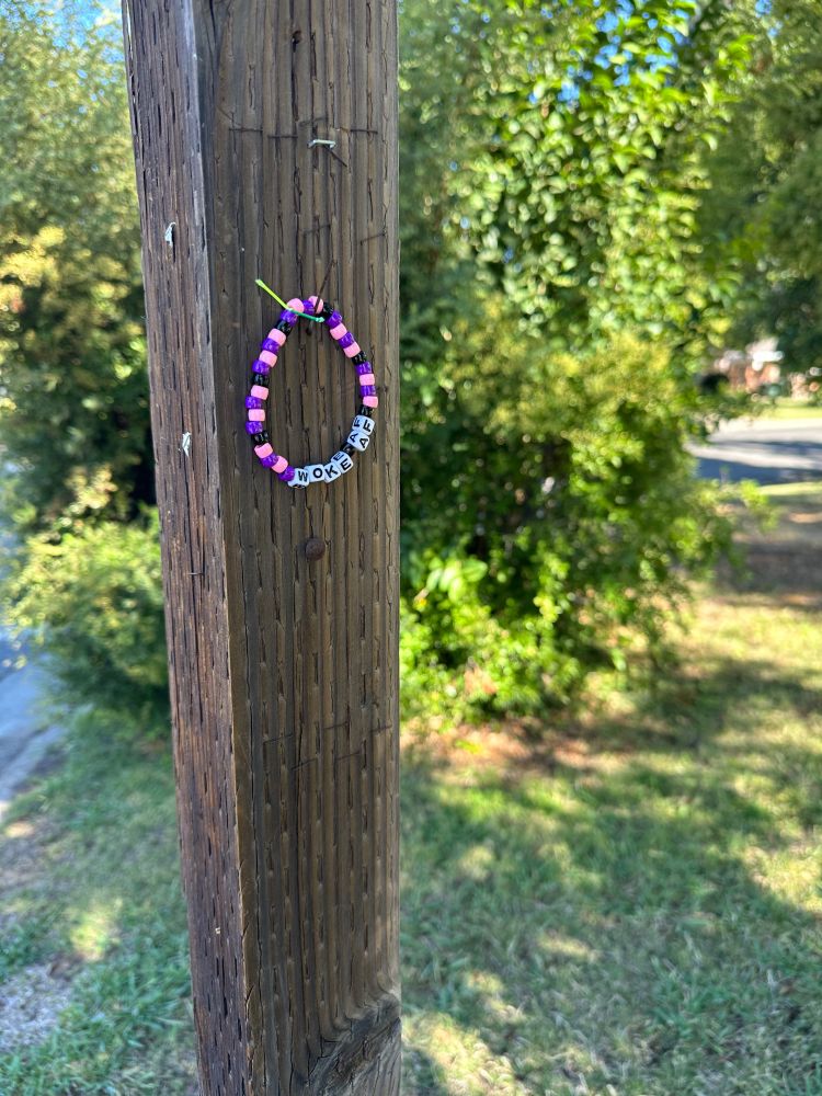 A Woke AF bracelet hanging on a street sign in a neighborhood
