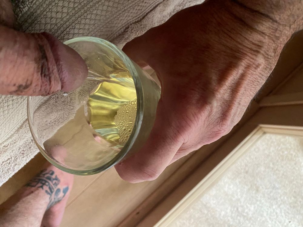 Guy pissing into a drinking glass