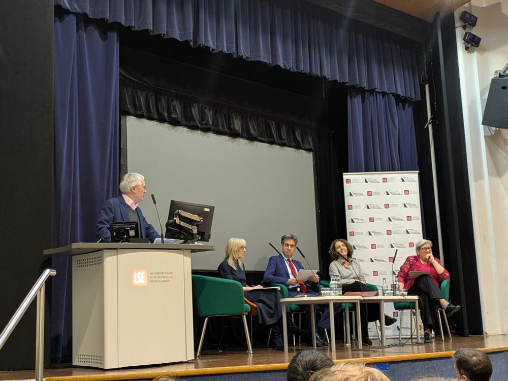 Lord Nicholas Stern stands on stage at a lecturn looking at a seated panel which includes Pete Betts' surviving party, UK energy and climate minister Ed Miliband, UK lead climate negotiator Kate Hughes, and UK climate envoy Rachel Kyte 