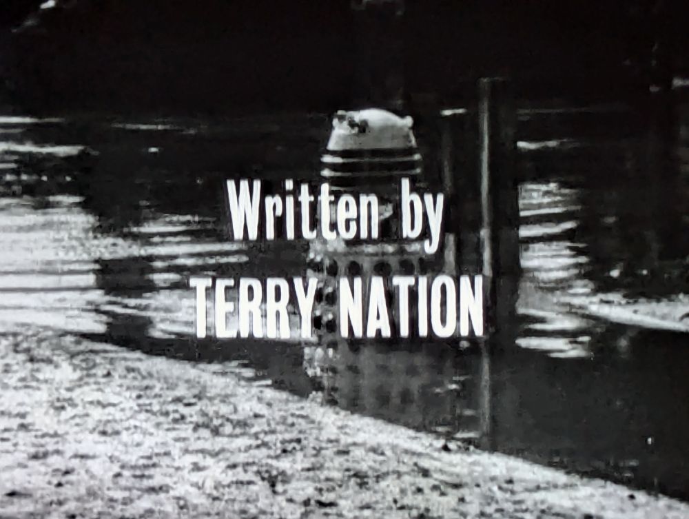 Grainy black & white photo of a Dalek with the words "written by Terry Nation" superimposed