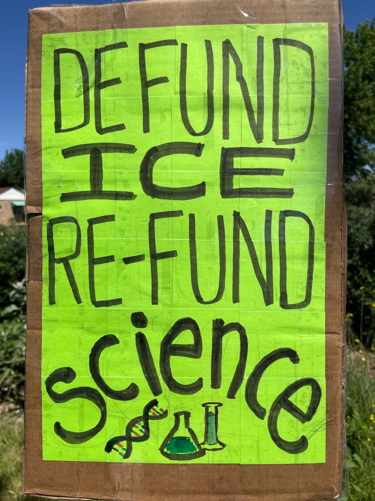 A handmade protest sign reads “DEFUND ICE, RE-FUND SCIENCE”