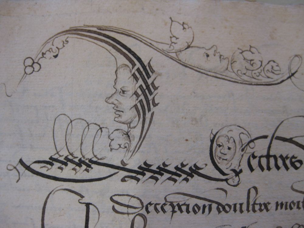Detail of a manuscript page with fancy pen strokes to make an initial L ornamented with leaves and berries. The L is decorated with a man's face in profile looking left from the up-stroke, a generic face looking upwards from a horizontal flourish, and a small impish face with a jester's hat tucked between the end of the L and the start of 'ectres'.