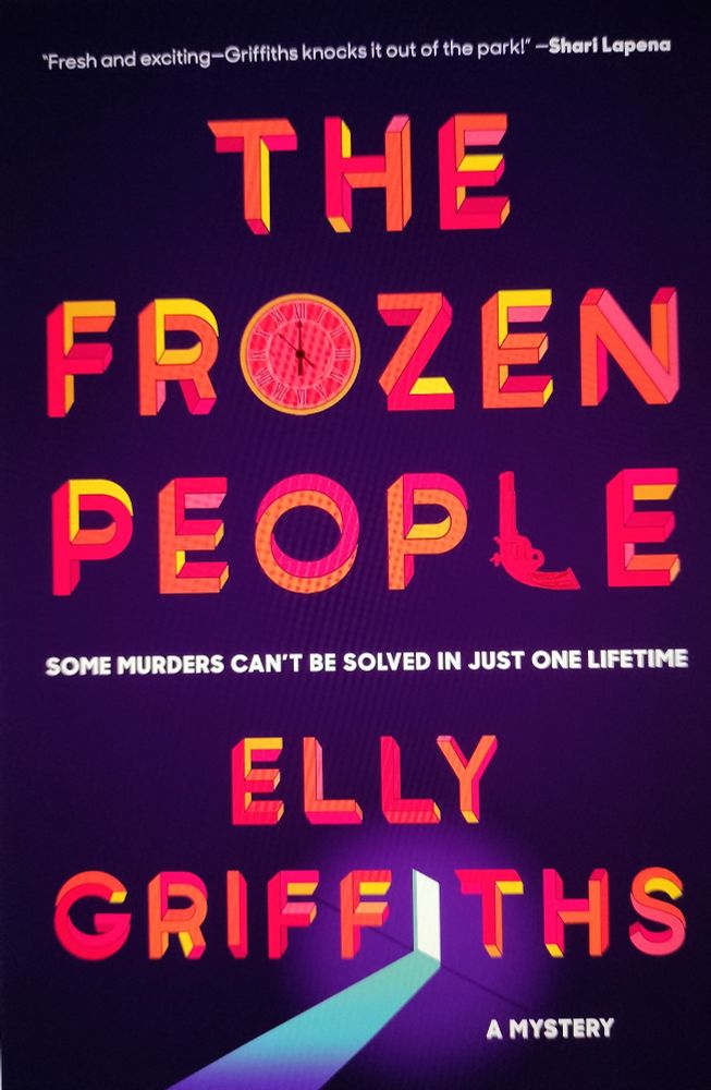 Book with black cover and red and white lettering: THE FROZEN PEOPLE: SOME MURDERS CAN'T BE SOLVED IN JUST ONE LIFETIME. A MYSTERY. The second i in Griffiths is an open door letting in a stream of blue light. 