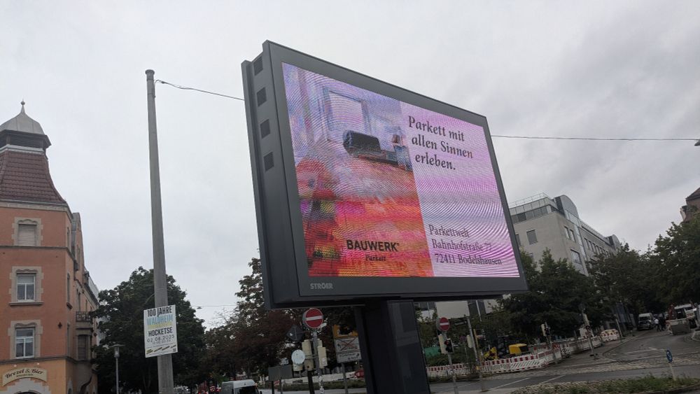 Werbedisplay in der Stadt mit einer Werbung mit dem Claim „Parkett mit allen Sinnen erleben.“