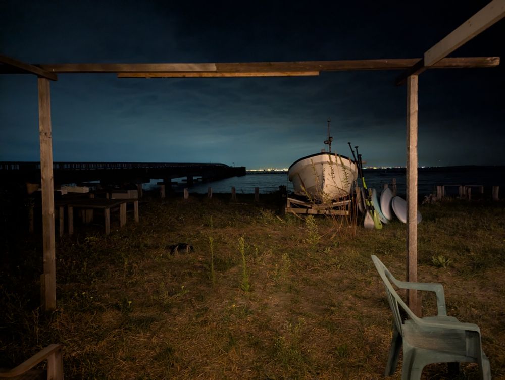 A boat pulled up on the shore, with a chair and a half-lit aky