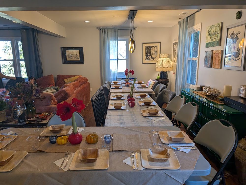 3 tables set in an L shape. You can see a coral couch on the left, red flowers and mini pumpkins.
