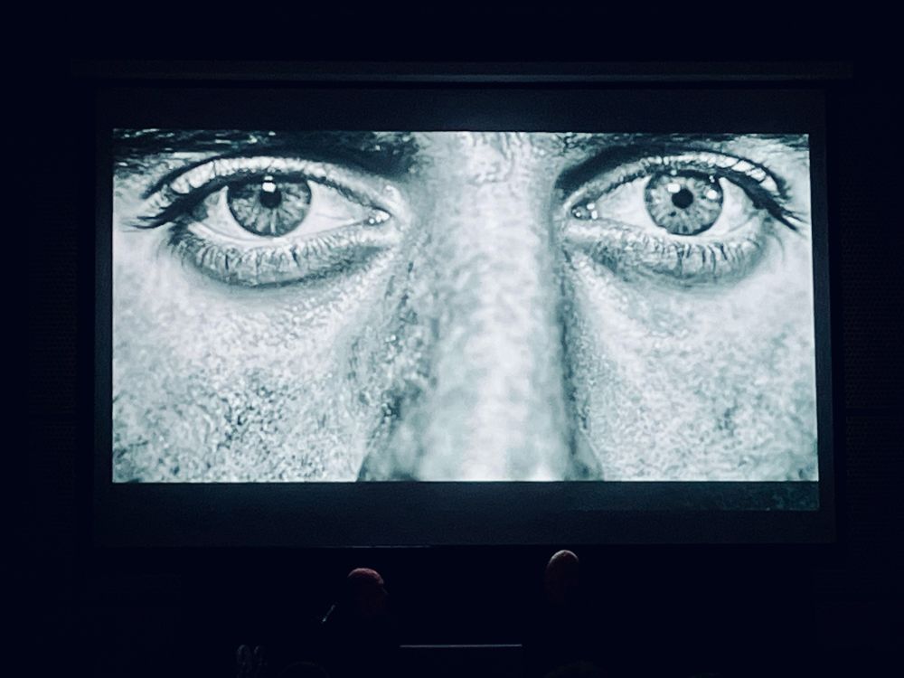 Video projection of close up of a man's eyes above the stage during a concert by electronic musician Vince Clarke