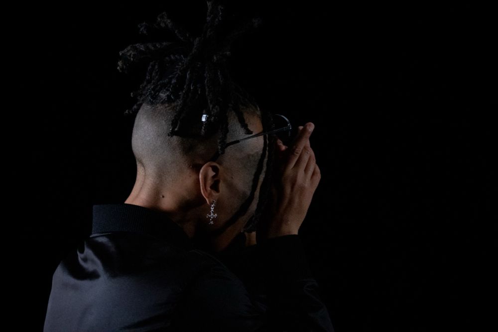 Medium close up portrait photo against black background, back of head 