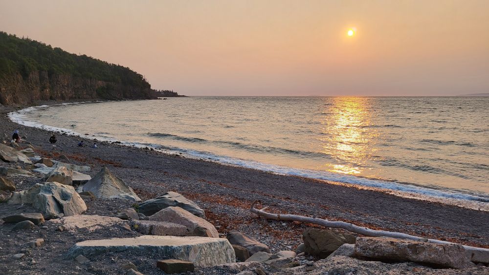 The beach behind the Halls Harbour lobster pound. A setting hazy sun.