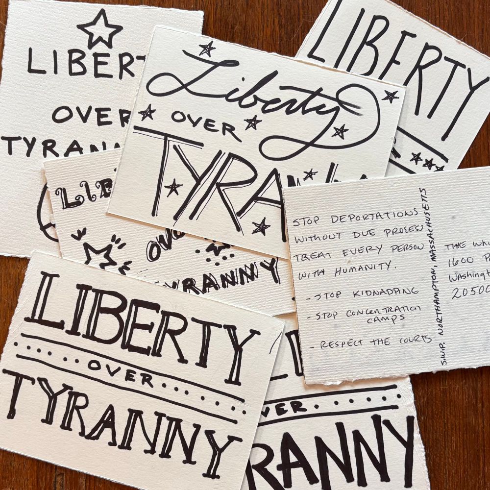 A pile of white postcards with black hand written text that says “liberty over tyranny” . One post card is turned over so you can see it’s addressed to the White House. The text says, stop deportation without due process. Treat every person with humanity. Stop kidnapping. Stop concentration camps, respect the courts. 