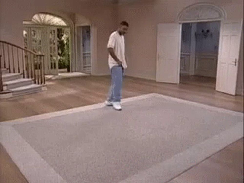 a man is standing on a rug in a living room with stairs .