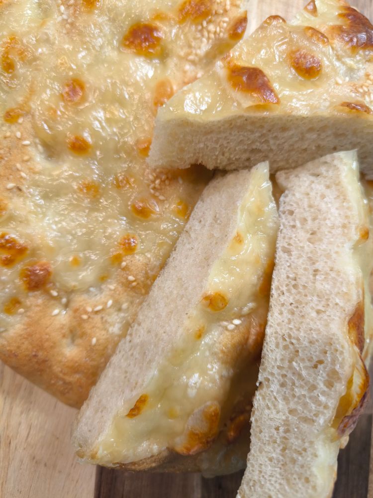 Fladenbrot mit Mozzarella überbacken, von oben gesehen. Teilweise mit Anschnitt. 