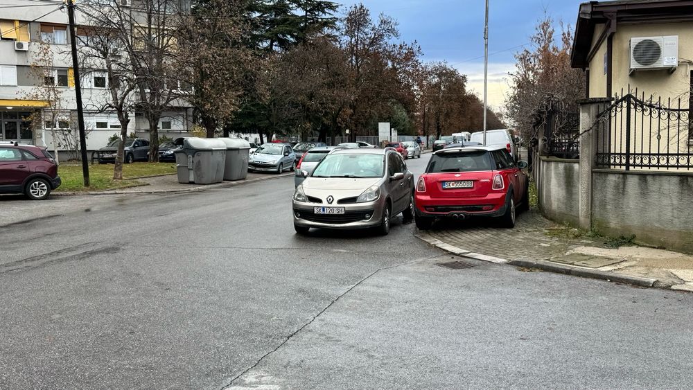 Car parked on the sidewalk and car parked outside of it in a crossing. 