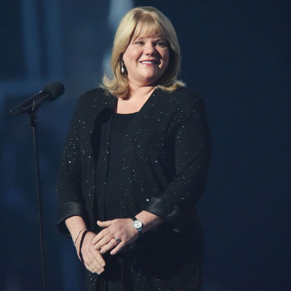 Andrea Swift in a sparkly black outfit standing on a stage