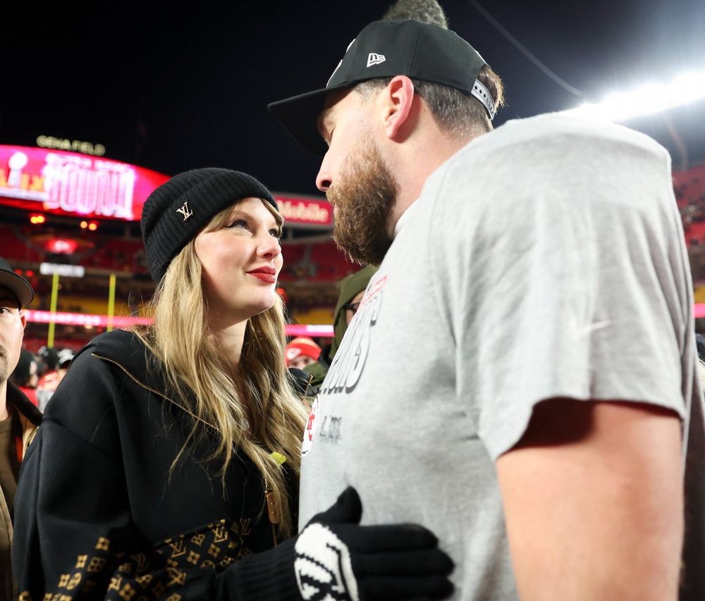 Taylor Swift and Travis Kelce looking at each other smiling on the field at arrowhead stadium Jan 26 - afc championship