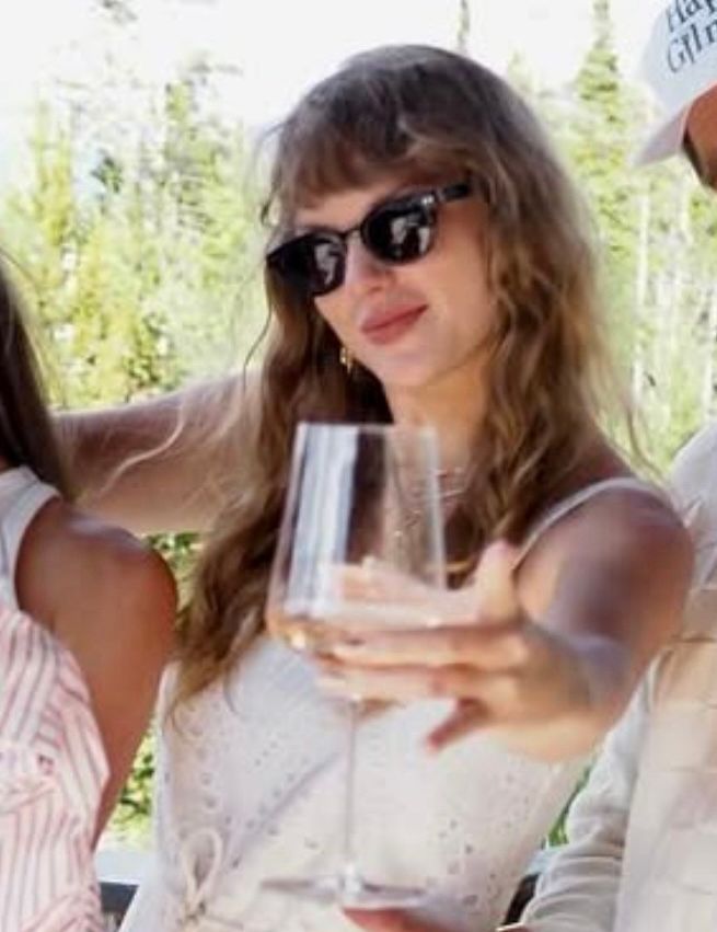 Taylor Swift posting for a picture, holding a wine glass out to the camera. She’s glowing and looks so peaceful and happy 
