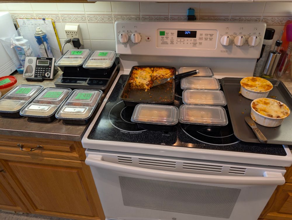 Meal prep meals laud out on stove and counter waiting to cook and be put in freezer. 