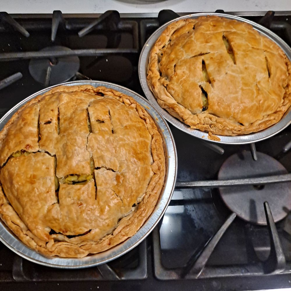 two savory pies with a top crust, into which a the letters H and T are coarsely carved