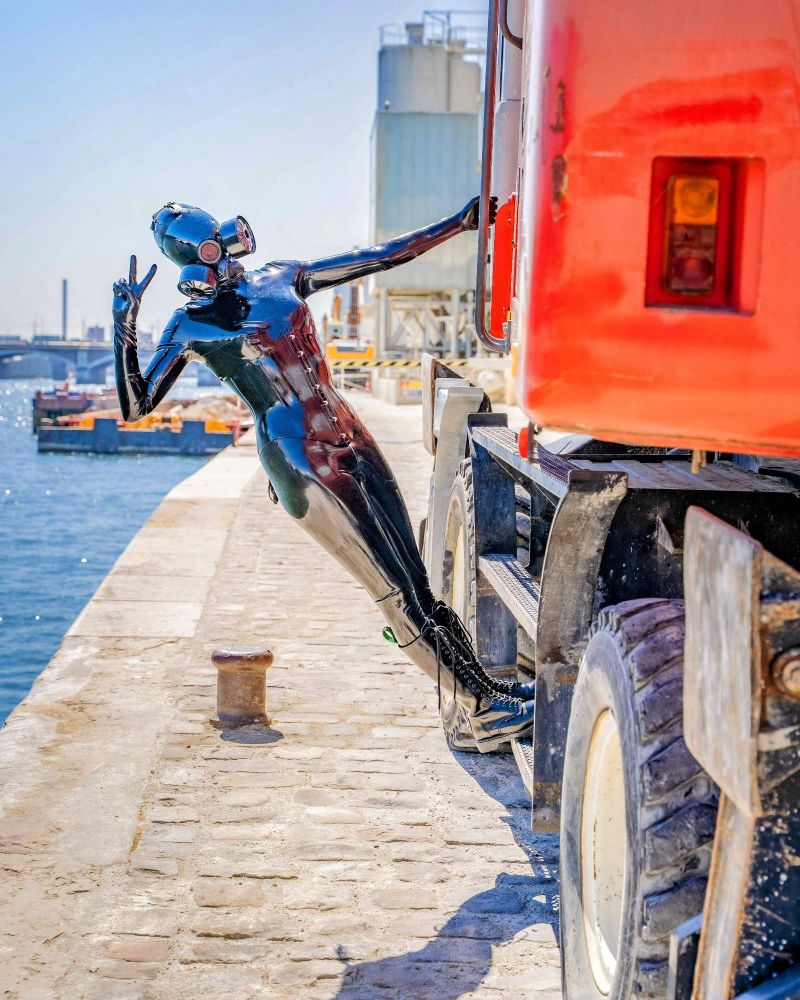 A latex drone on the ladder of an excavator doing a peace sign on the border of the Sene river, in Paris.