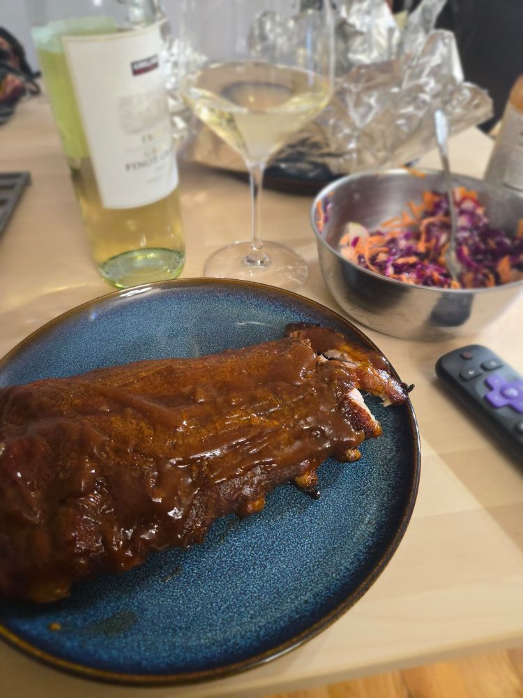 Smoked pork ribs colorful coleslaw and a bottle of wine