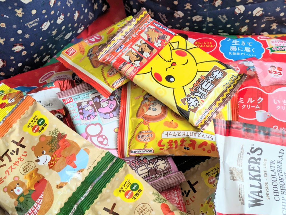 ビスケットやチョコレートなど色々なお菓子と、サンタクロースと雪だるまの包装紙が写っている。