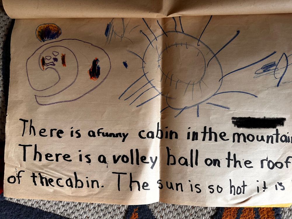 Page 5 of the story book. 

It’s a drawing of a swirl on the left that looks vaguely like a yin-yang Casper the ghost mashup, a big blue sun and squiggles.

The story continues “there is a funny cabin in the mountains. There is a volleyball on the roof of the cabin. The sun is so hot it is (continued on next page)