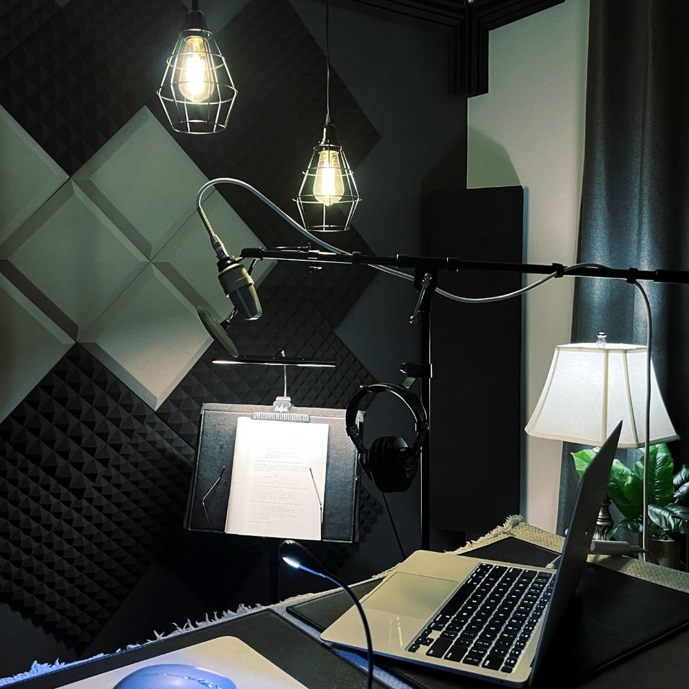 A cozy home recording studio featuring a microphone, mood lighting, and a laptop on a desk, creating a comfortable workspace.
