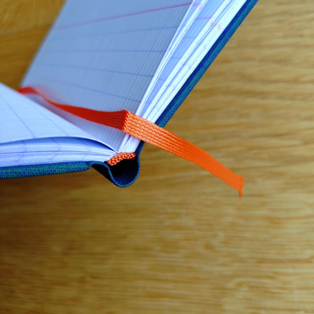 detailansicht der unterkande des notizbuches mit orangefarbenem kapitalband 