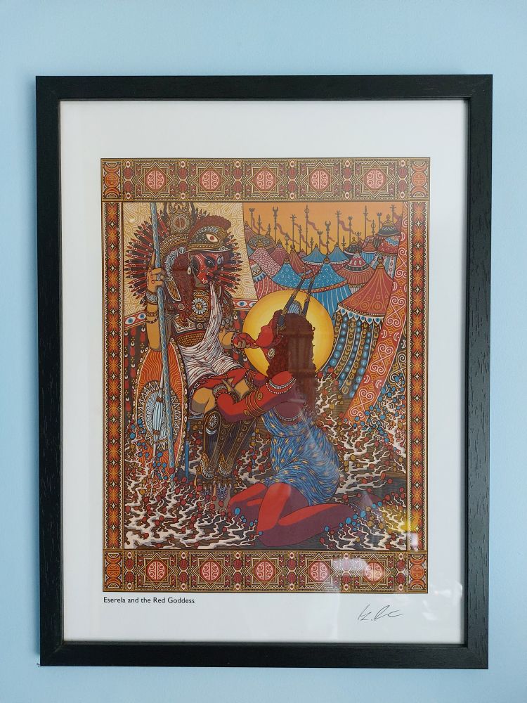 A colourful picture in a frame. In the white border it says Eserela and the Red Goddess, and the artist's signature is visible. The picture is full of complicated detail. A warrior woman sits to the left, with an ornate shield and a spear. She looks tenderly at a red-skinned woman kneeling on the right, softly touching her chin. The kneeling woman is highlighted with a golden halo, and wears a blue dress adorned with stars. Behind them, we can see many tents, like an army encampment.