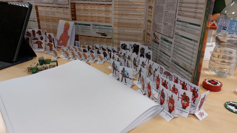 Lots of colourful cardboard standees wait behind a GM Screen.