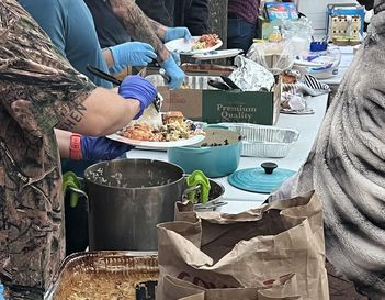 Food Not Bombs volunteers serve food outside to hungry. 