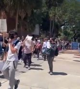 Students march on campus with signs. 