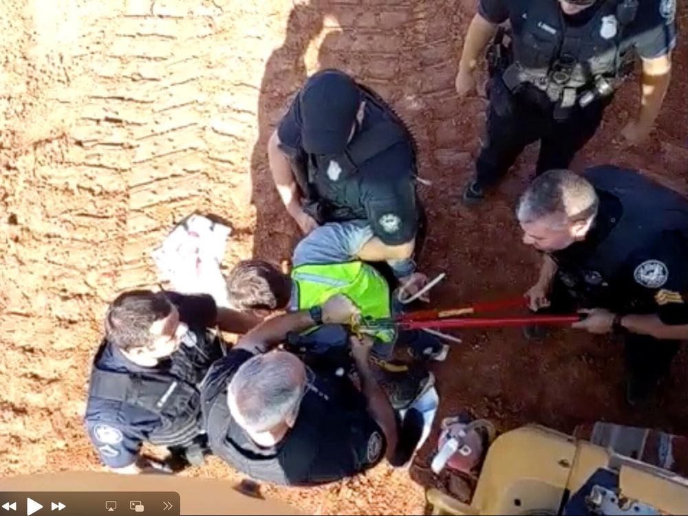 Police attempt to remove protester who has locked down to equipment.
