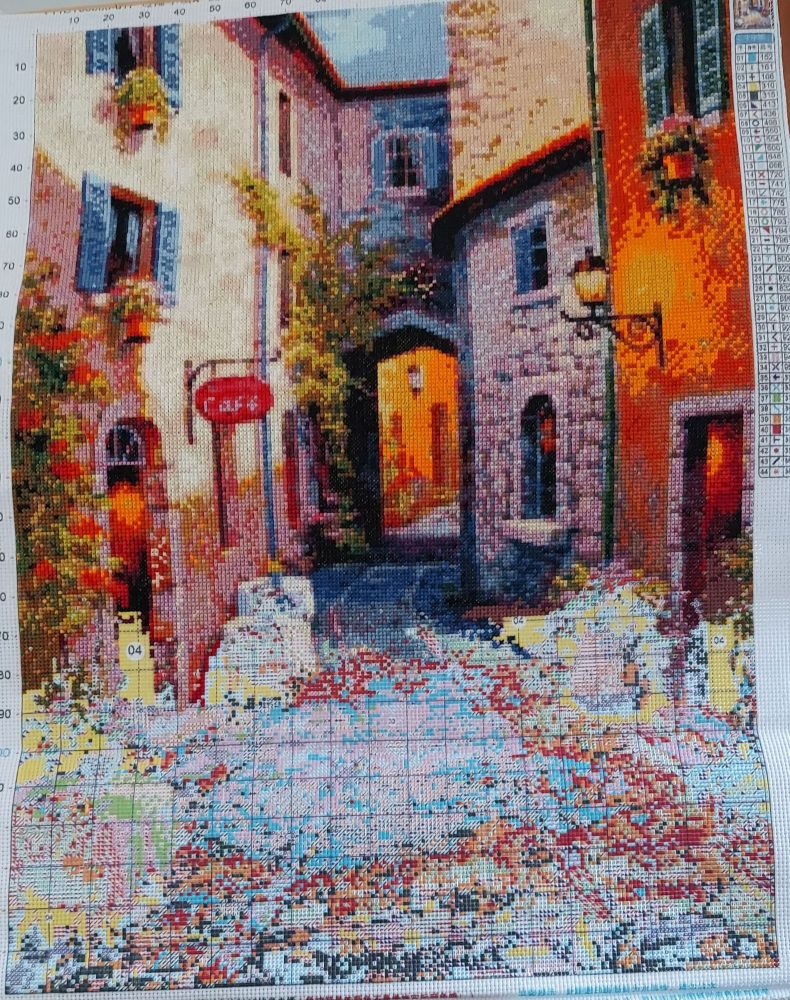 A picture of a narrow street of shops in a small European village at sunset.