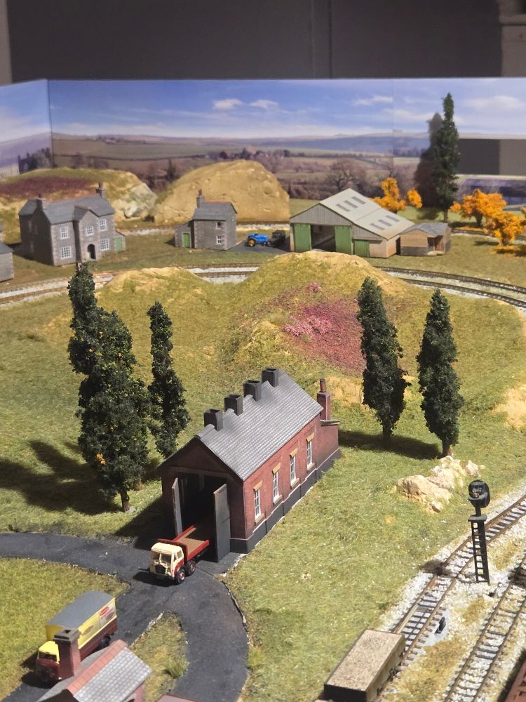 5 model fir trees on a model railway layout.