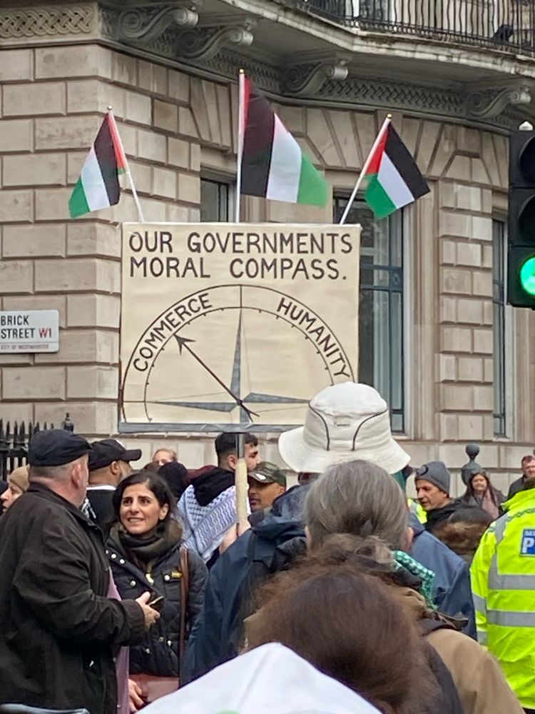 A huge banner at the demonstration showing a compass with Commerce and Humanity at each end 