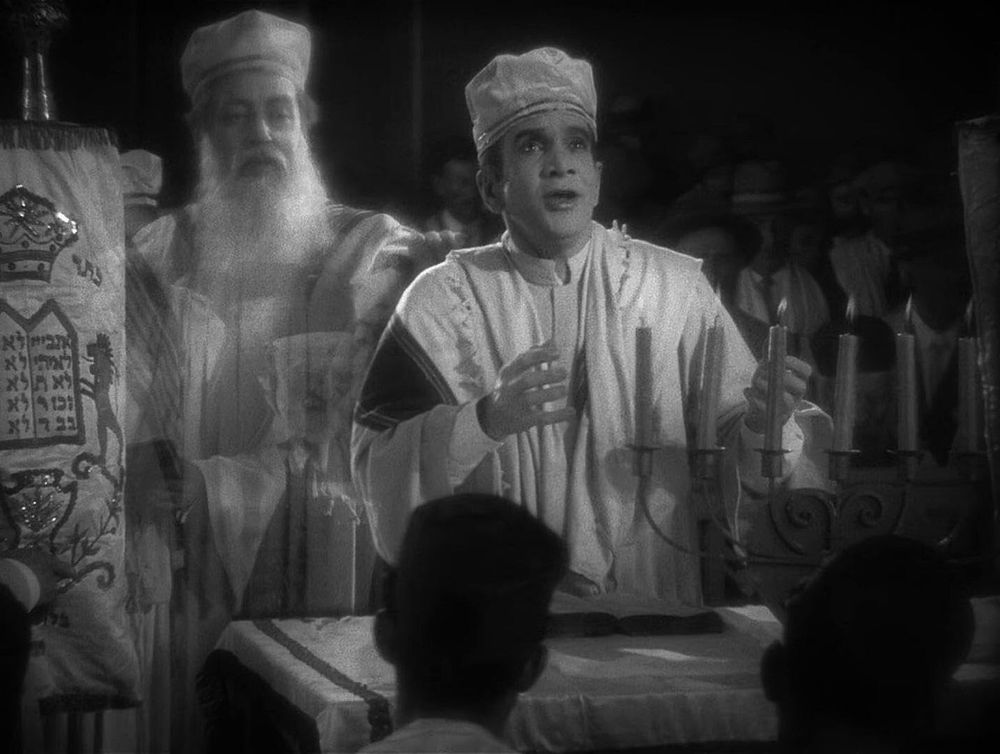 Still from The Jazz Singer (1927): Al Jolson in Jewish cantorial robes praying for a congregation, with Warner Oland as the spirit of his Orthodox father behind him