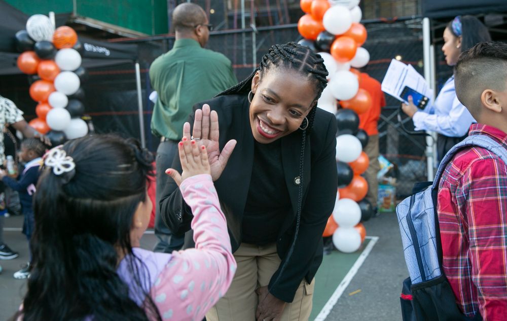 A picture of Councilmember Rita Joseph high fiving a child and smiling>
