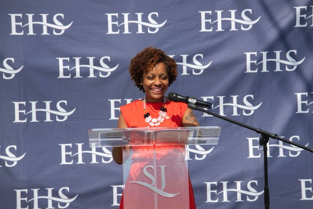 CM Brooks Powers speaking at a podium in front of a backdrop that says EHS