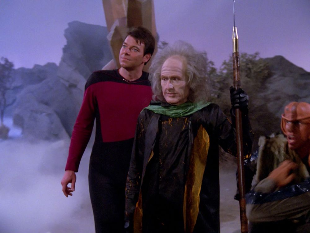 Riker and a T’Kon soldier discuss how awesome humans are as the Ferengi look on enviously. 