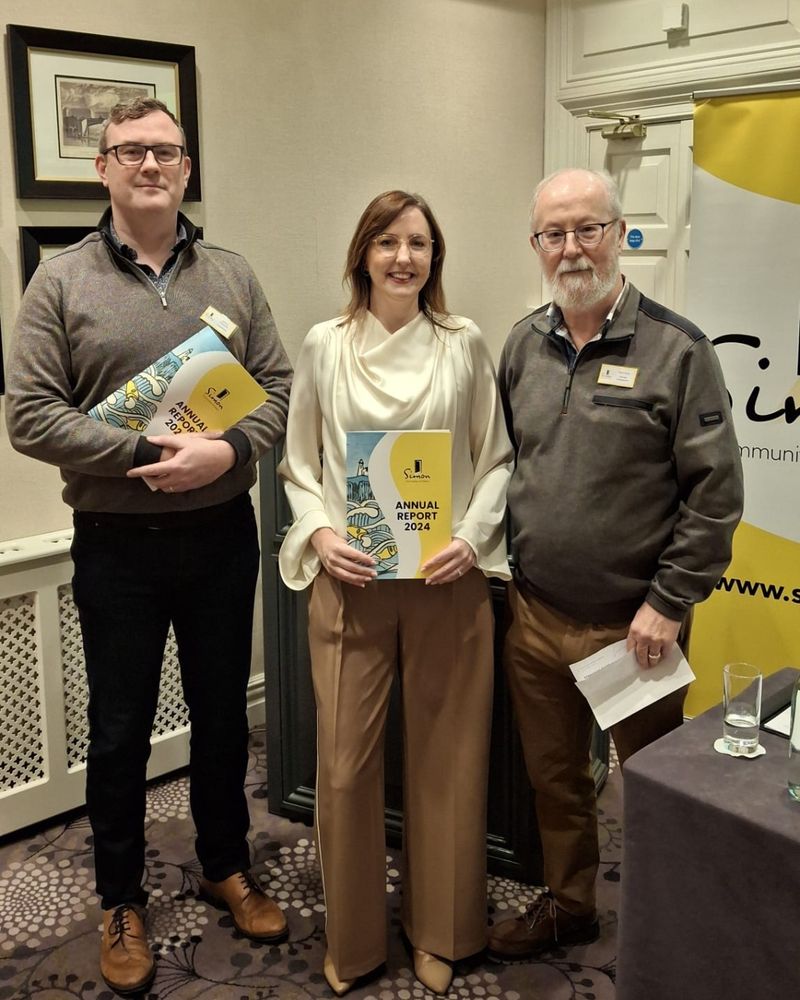 Johnny O'Rourke, Ber Grogan and Mick Price all smile to the camera. The photo was taken at the Annual Report Launch 2024, they all hold reports in their hands.