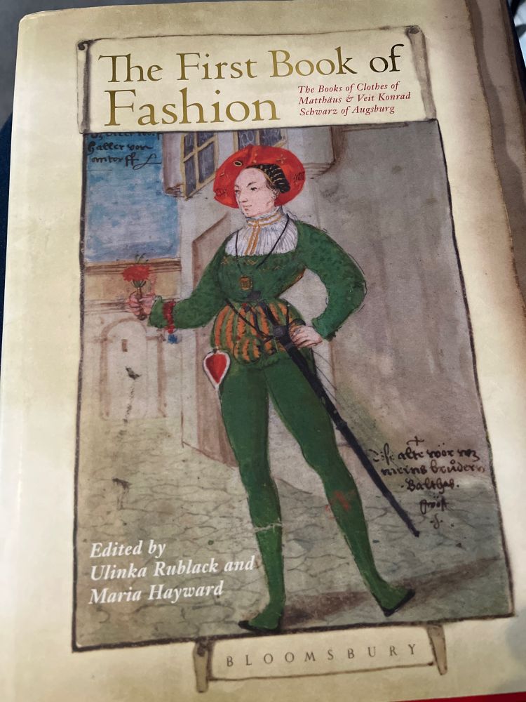 The cover of a book entitled ‘The First Book of Fashion’. It features a portrait of a nattily dressed young man in green doublet and hose.